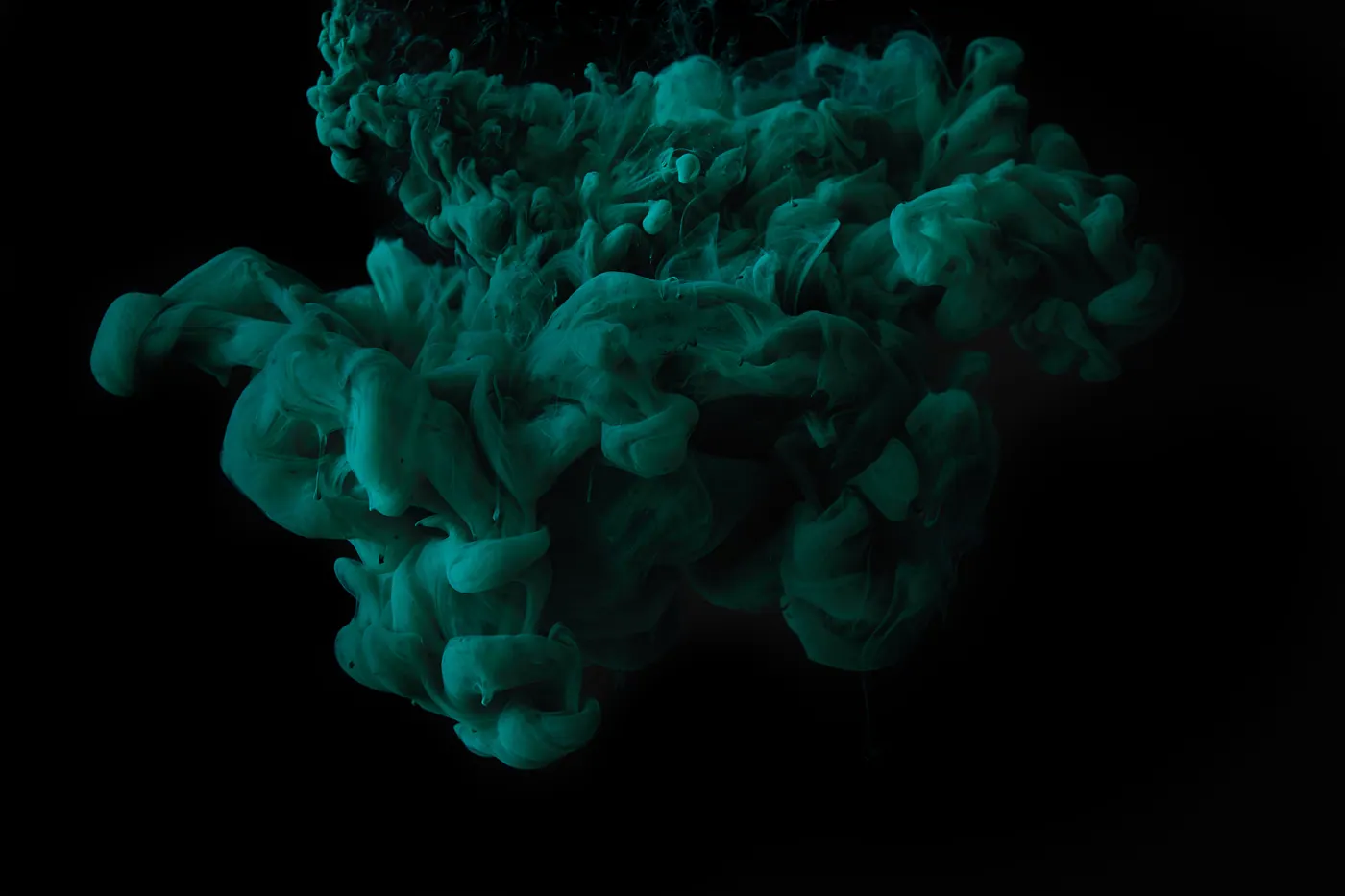 Green teal ink smoke on black background